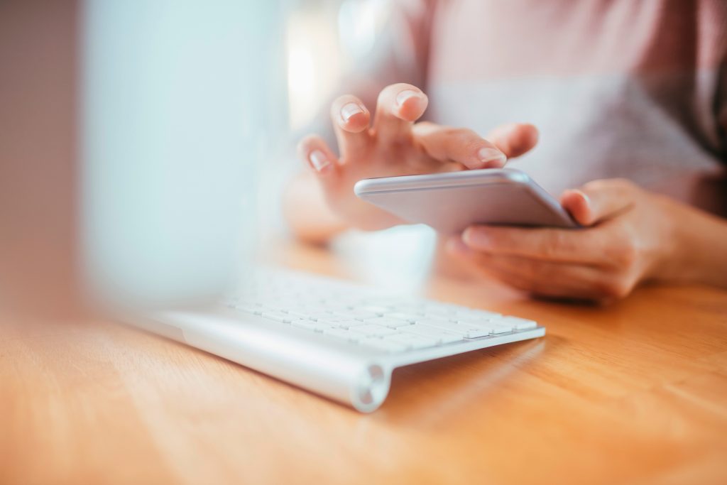 Young woman empowering her self using a smart phone for Budgeting while reading our privacy policy on her computer.