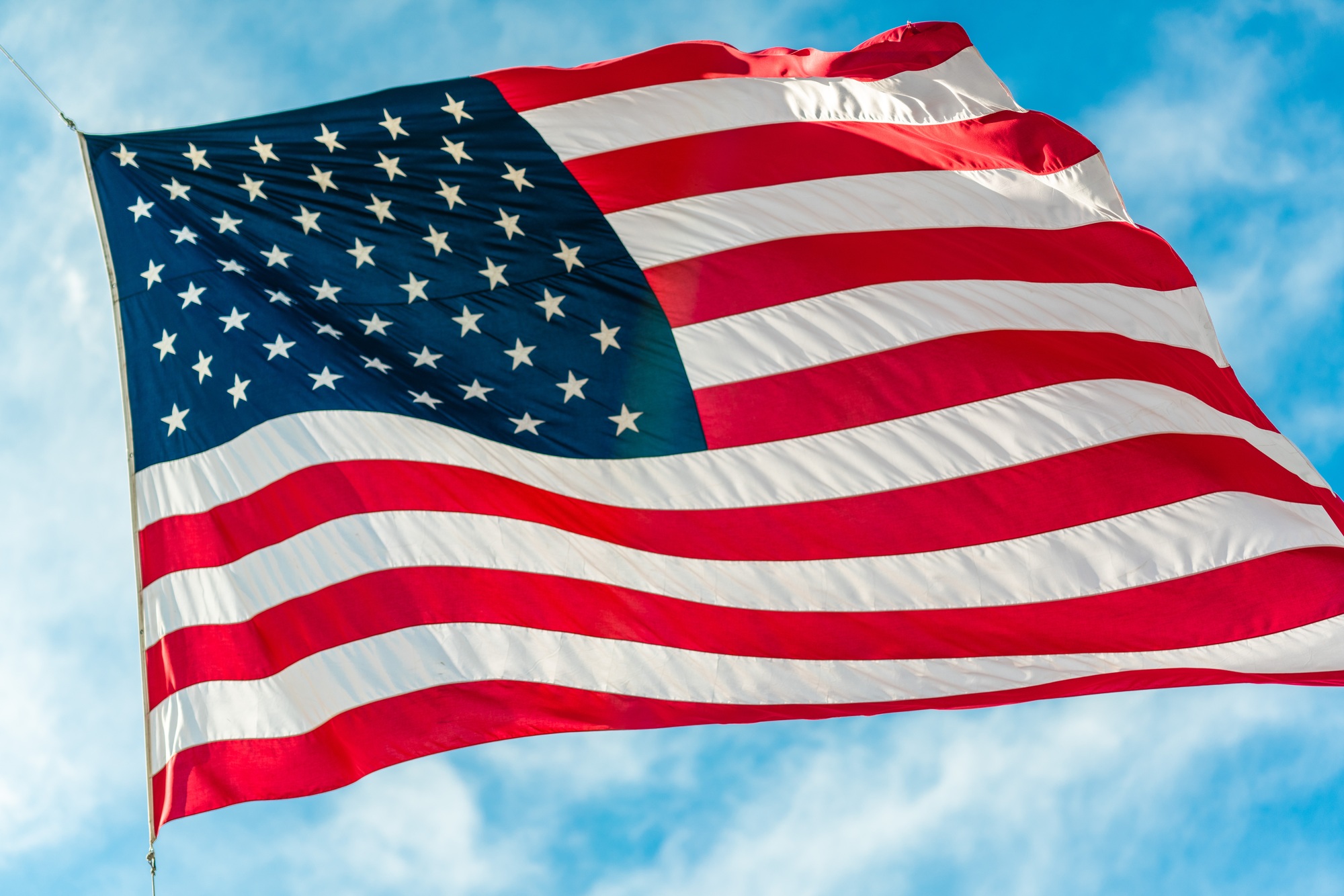 American flag waving in blue cloudy sky