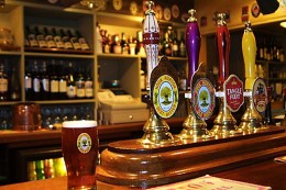 Picture of three beer pumps and a pint a pint glass.