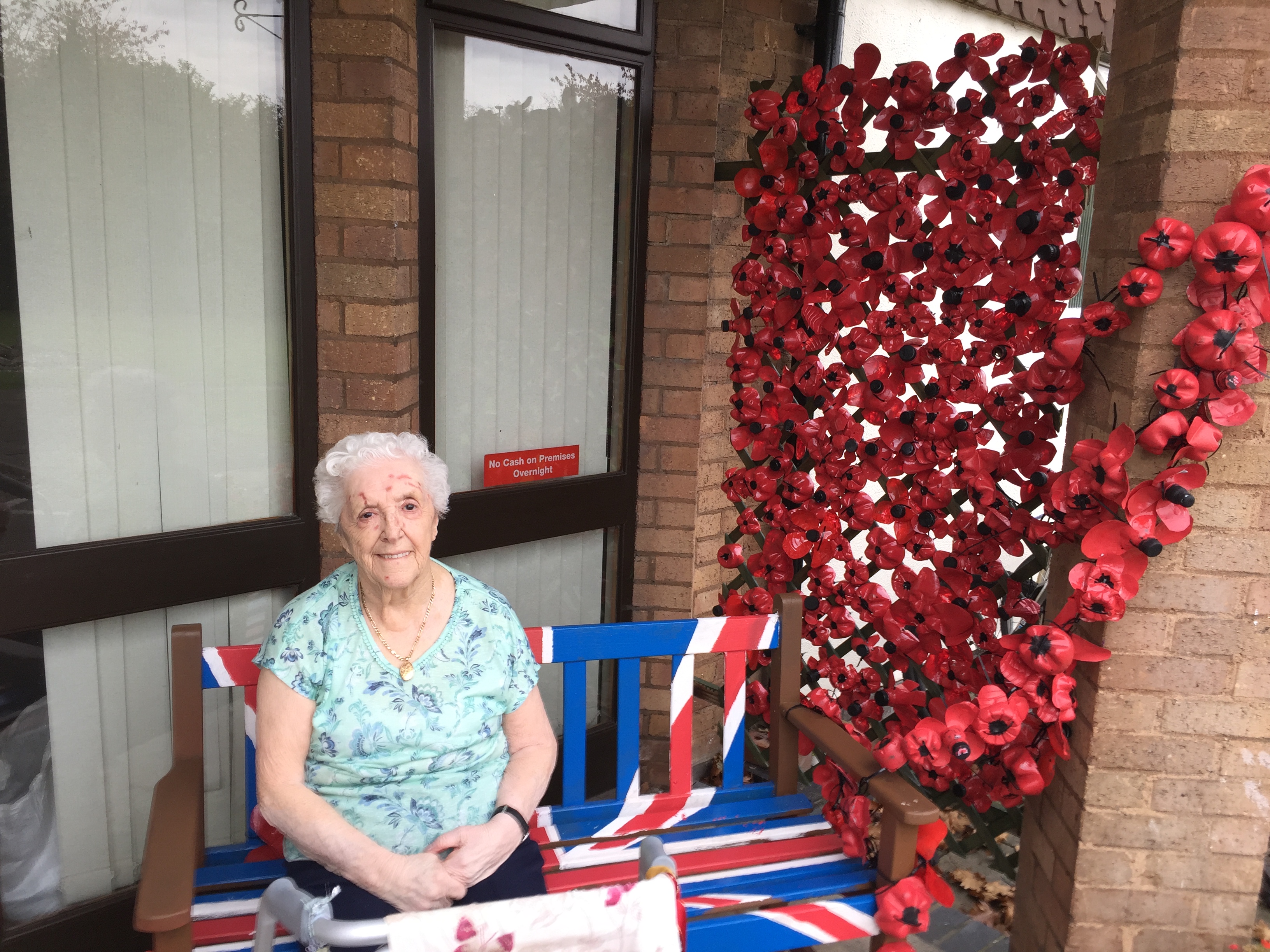 A resident of Fosse House sat with the poppy memorial