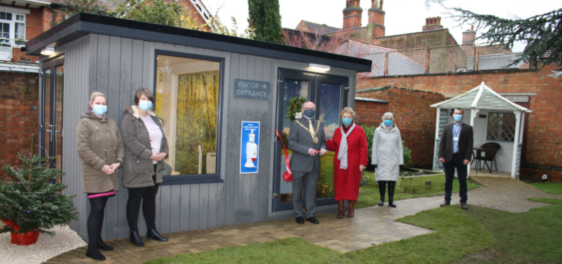 The Mayor of Rugby, Cllr Bill Lewis, celebrating the opening of New Directions’ COVID-secure pods. The pod is separated with glass to allow people to visit their relatives safely and without the need for masks. 