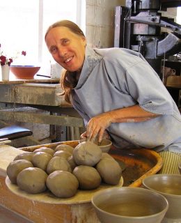 A photo of Heather Ducos with a lot of clay. She is smiling.