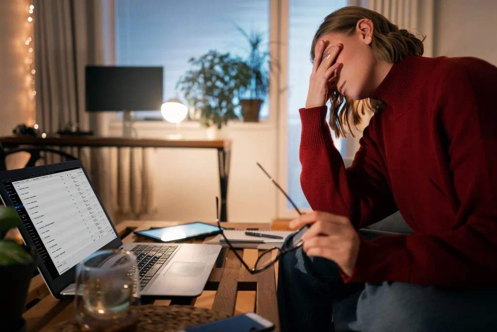 Billedet forestiller en træt og frustreret person foran end computer, der har brug for hjemmeside hjælp