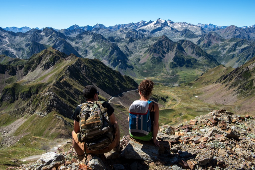 Twee wandelaars genieten vanop een bergtop van het uitzicht over de Pyreneeën.