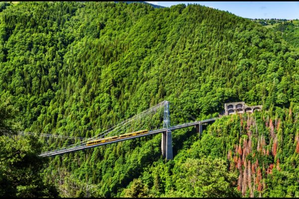 Gele trein rijdt over een brug in de Pyreneeën.