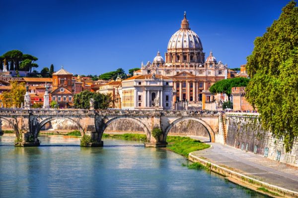 Zicht op de rivier Tiber in Rome, met een brug en de Sint-Pietersbasiliek op de achtergrond.