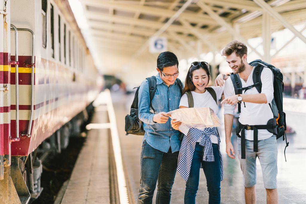 Drie vrienden op het treinperron kijken samen op een kaart. ©Shutterstock
