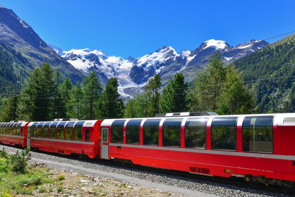 De bekende Zwitserse trein Bernina Express op een zonnige dag met bergen op de achtergrond.