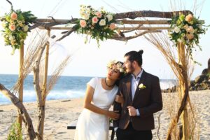 couple sous une arche fleurie sur une plage