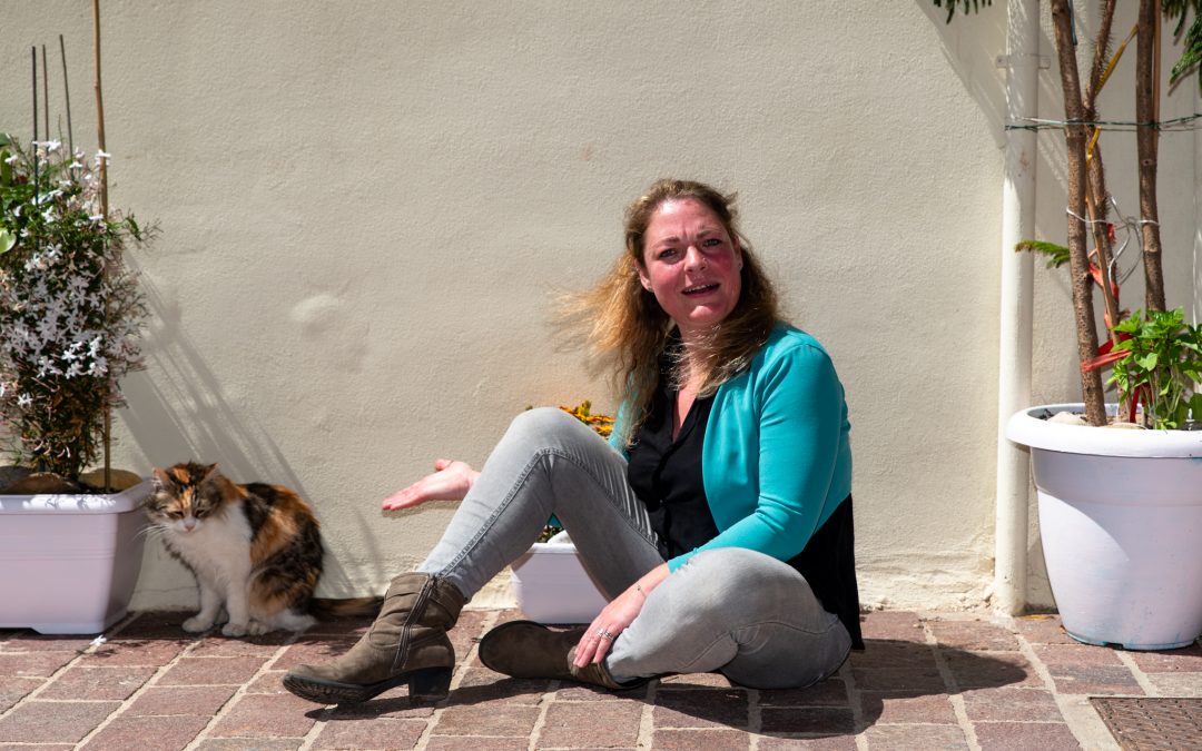 Lydia sitzt am Boden in der Altstadt von Chania und versucht die Aufmerksamkeit einer Katze zu bekommen