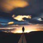 a person standing on a road at sunset