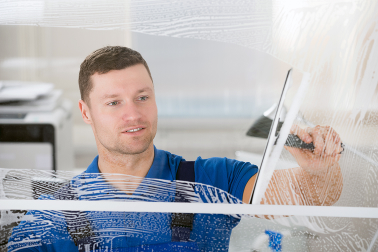 Worker Cleaning Soap Sud On Window With Squeegee