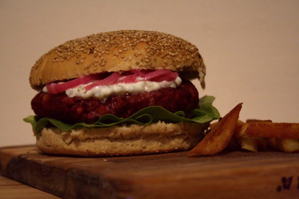 recept voor huisgemaakte vegan hamburgers met een broodje met rode ui, sla en saus