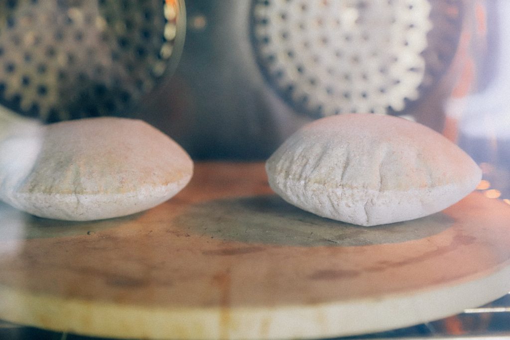 Volkoren pitabroodjes die opbollen in de oven