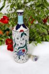 Ceramic floral bottle with colorful tulip motifs. Red, green and blue color nuances on a white backdrop 