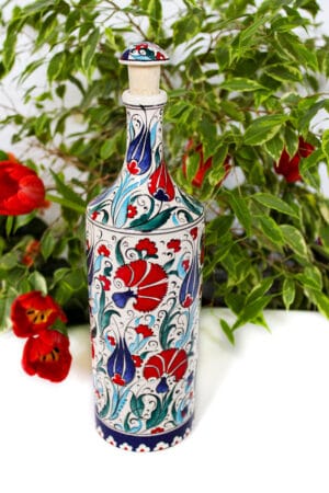 Håndlavet farverig keramik flaske med motiver af nelliker og tulipaner i røde, blå, turkise og grønne farver. Håndmalet låg