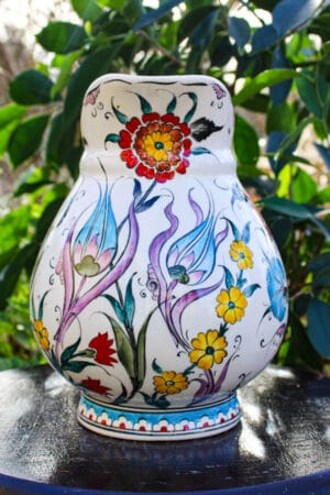 Rund keramik flaske med turkisfarvet hank og blomstermotiver
