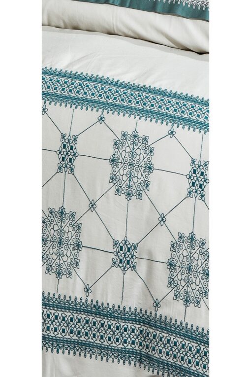 Organic bed linen with embroideries and motifs in blue green colors . Flowers and geometrical forms