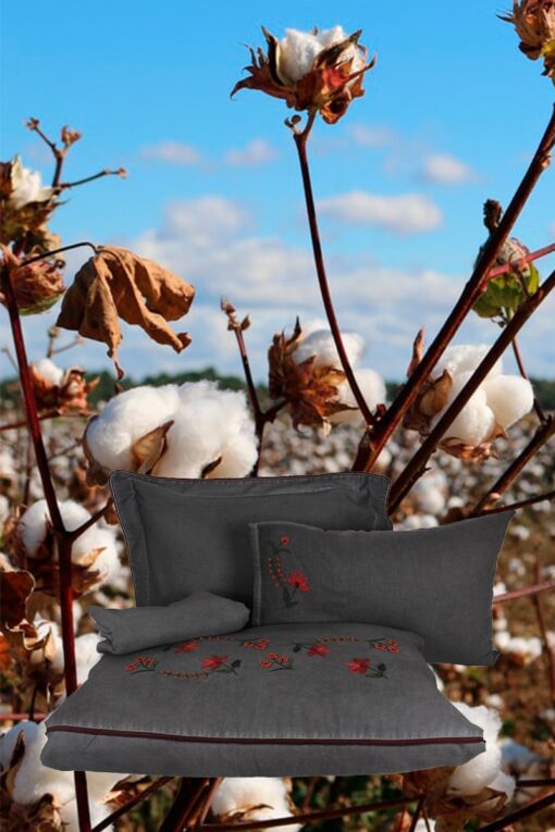 Organic duvet cover set floating on a background of an organic cotton field. Anthracite grey cotton satin bed linen with handmade embroideries