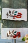 Handmade embroidery with elegant red pompons decorating a dusty green towel border