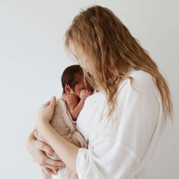 Mamabel mom holding and kissing her newborn