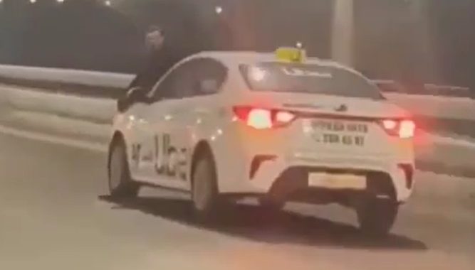 In Rusland neemt een Uber-chauffeur ook mensen mee op motorkap