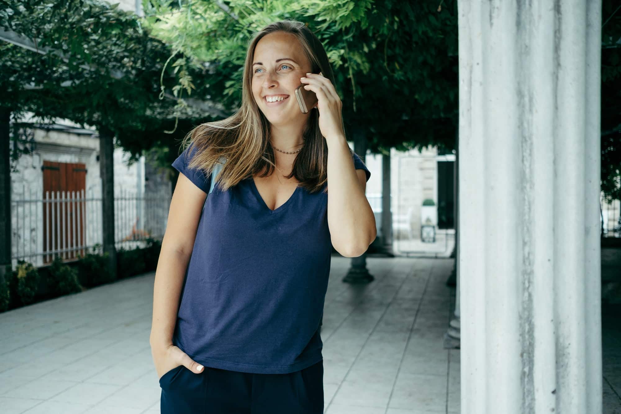 Woman portrait traveler in a blue T-shirt with a backpack talking by phone