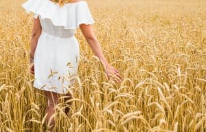 femme en robe blanche se promène dans un champ de blé