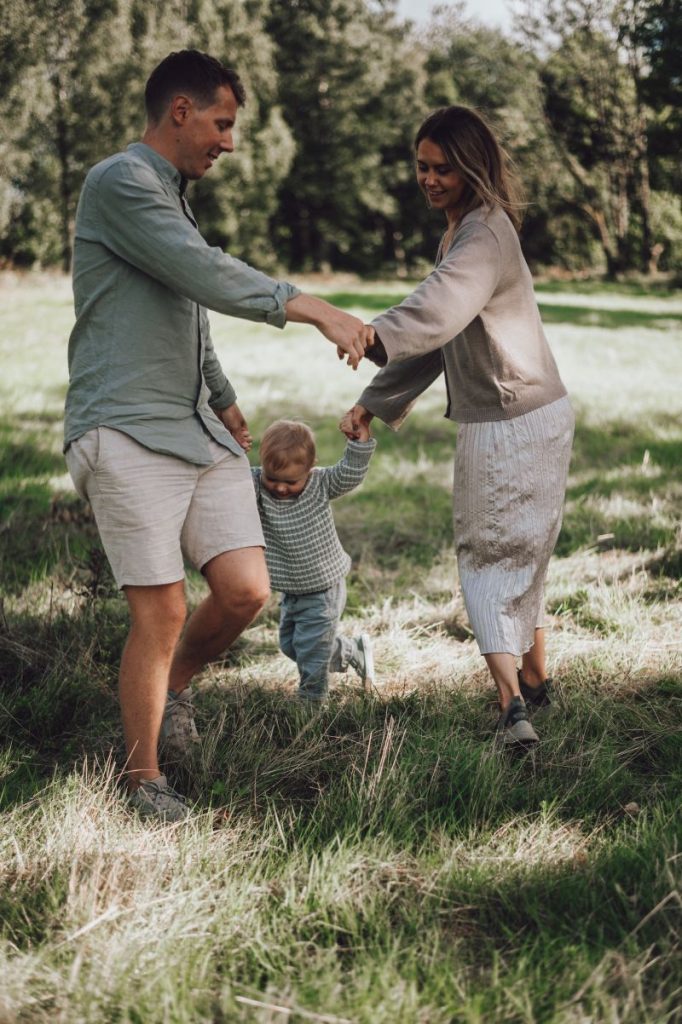 En familj som dansar tillsammans på en äng under en familjefotografering i Borås
