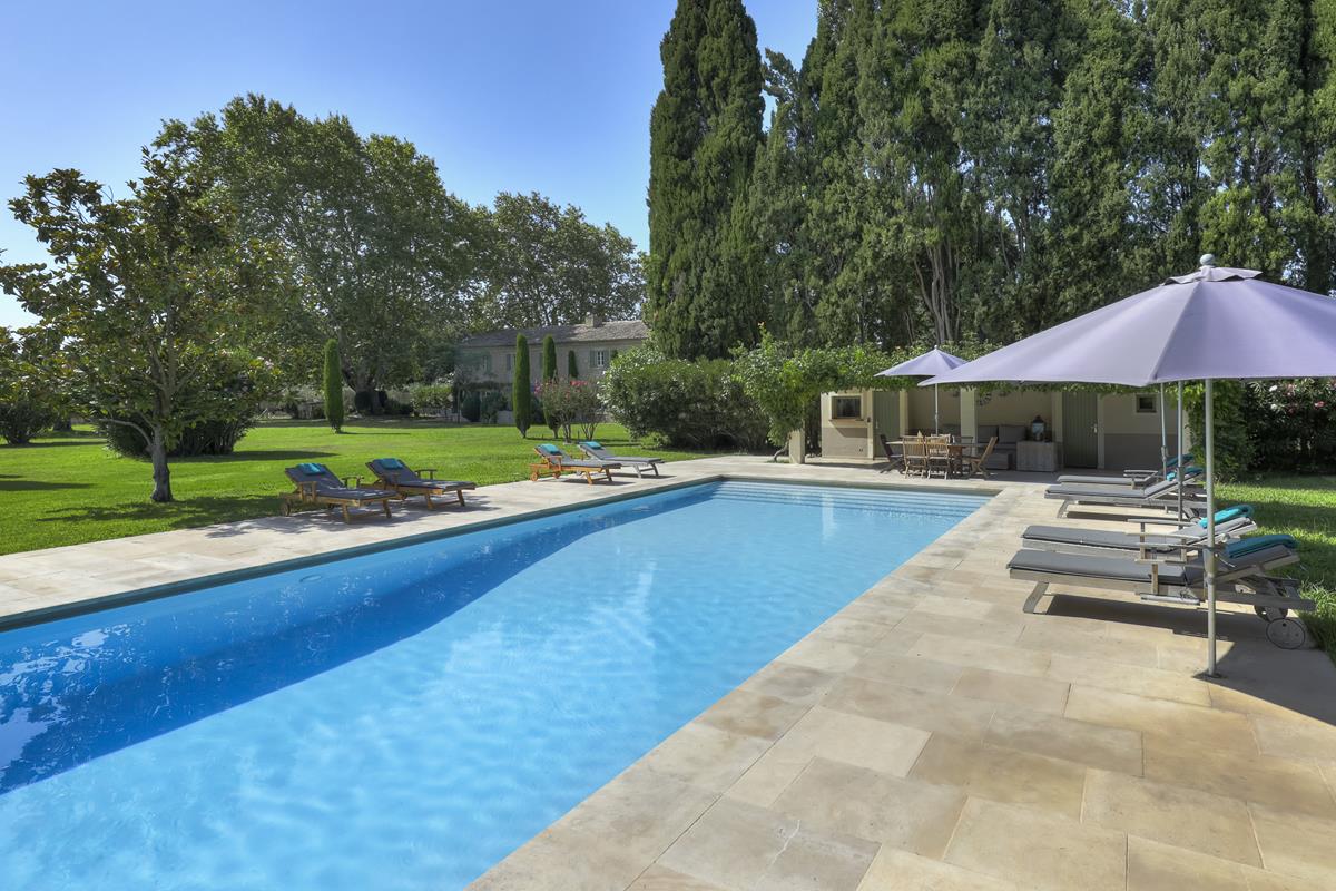 Outdoor swimming pool with sun loungers and umbrella.