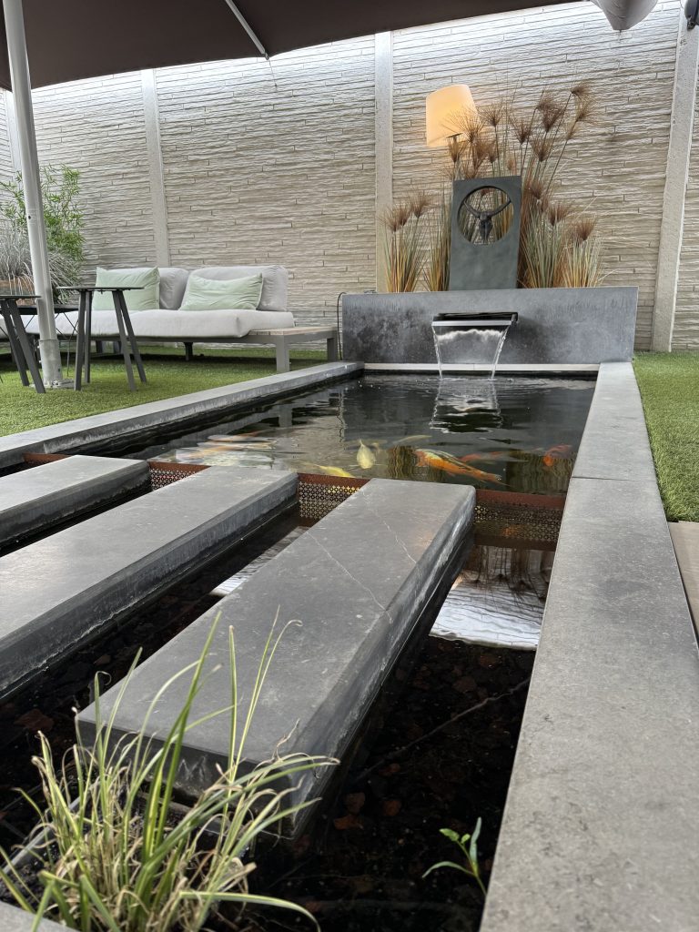 Koi pond at private spa dil-zen finished with bluestone stepping stones and edging and a fountain slot in the same material.