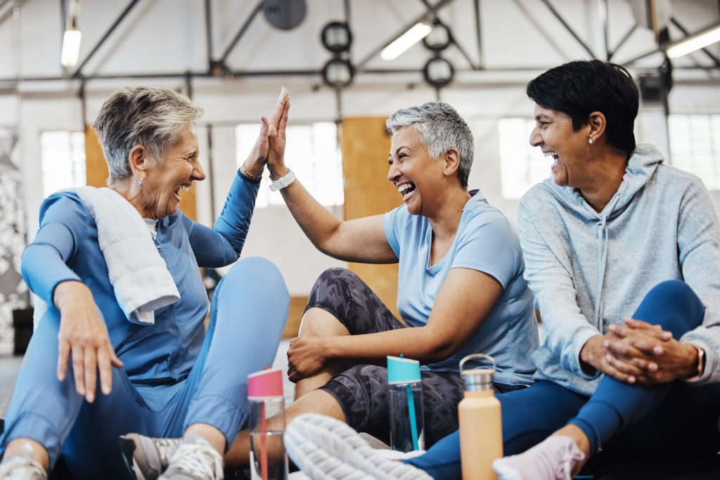 Gym, high five and group of mature women celebrate after fitness class, conversation and congratula