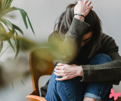 Anxiety, how can naturoapthy help with it? Lady sitting on a chair huddled, holding her head.