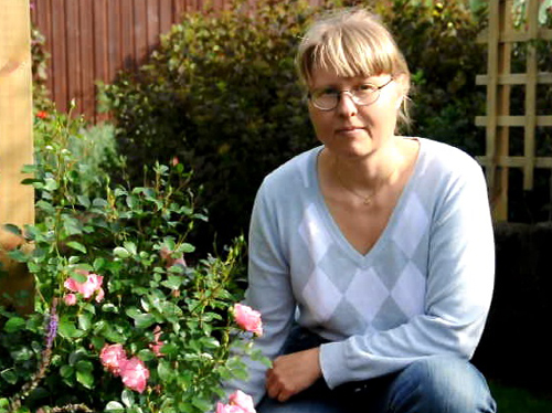 This is a picture of me, Carina Johansson sitting beside a rose in my garden.