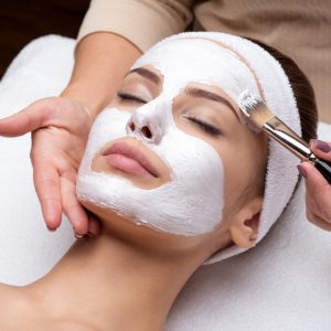 Kvinne som får hvit ansiktsmaske i hudpleiebehandling hos Medskin Beauty