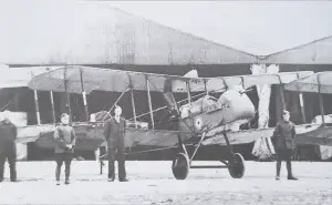 an old black and white photo of men standing in front of a plane