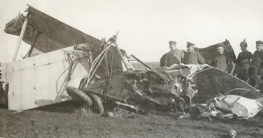 a group of men standing next to a wrecked airplane