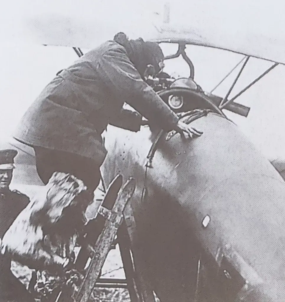 an old black and white photo of a man leaning on a plane