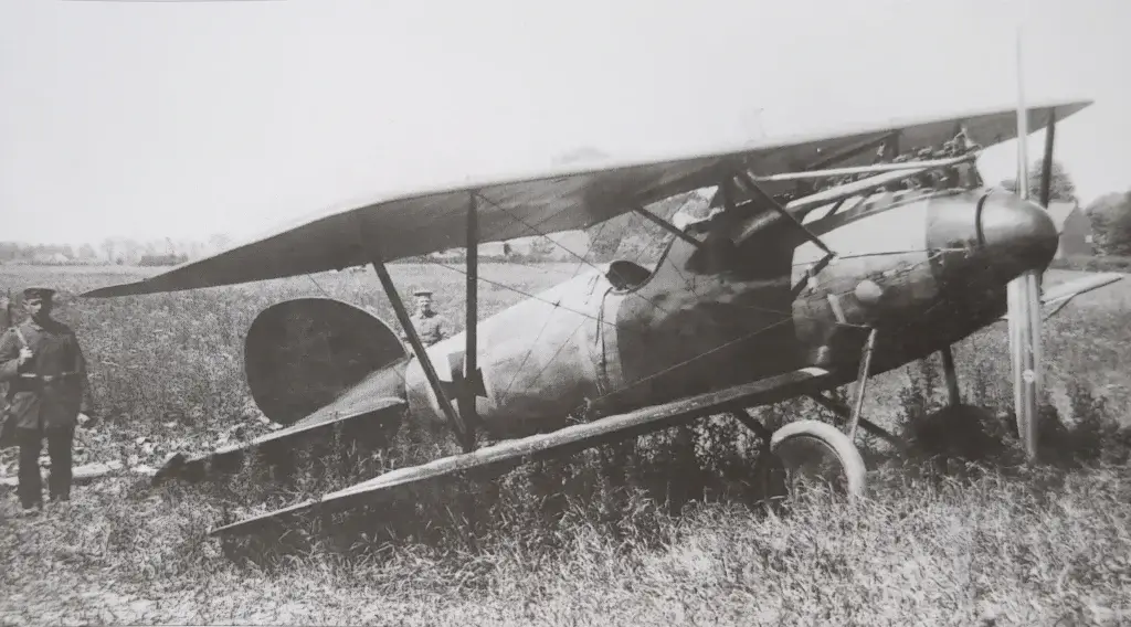 a man standing next to an old airplane in a field