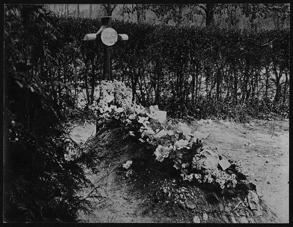 a black and white photo of a cross in the woods