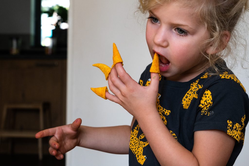 Meisje eet Bugle chips die ze op haar vingers heeft gedaan