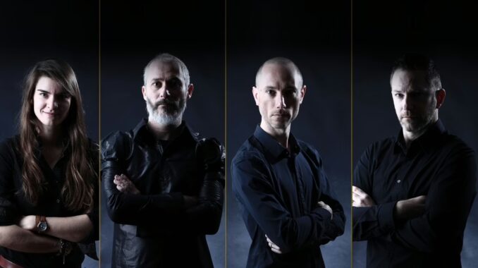 A band portrait of four members standing side-by-side against a dark backdrop, each with their arms crossed.
