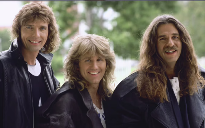 Triumph old photo from the '70s : '80s Old photo of Canadian hard rock power trio Triumph from the late '70s / early '80s. From left to right: Gil Moore, Rik Emmett, and Mike Levine. They're posing in front of green trees, smiling, and wearing black jackets