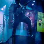 Carbon Killer, metal DJ performing live with an electric guitar in front of a set up with vertical screens.