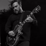 Black and white picture of Travis Stever, guitarist of Coheed and Cambria performing live.