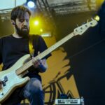 Bass player of Planet Of Zeus performing live. Yellow lights.