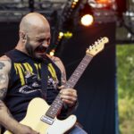 Singer and guitar player of the band Planet of Zeus performing live at Kave Fest. Yellow lights.