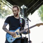 Guitar player of Ringscabs performing live. Trees and natural light in the background.