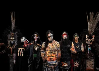 Five men staring at the camera all wearing face paint, dark black background with no image.