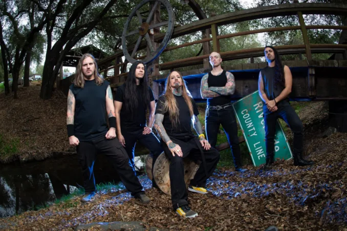 Five band members staring at the camera, wooded background